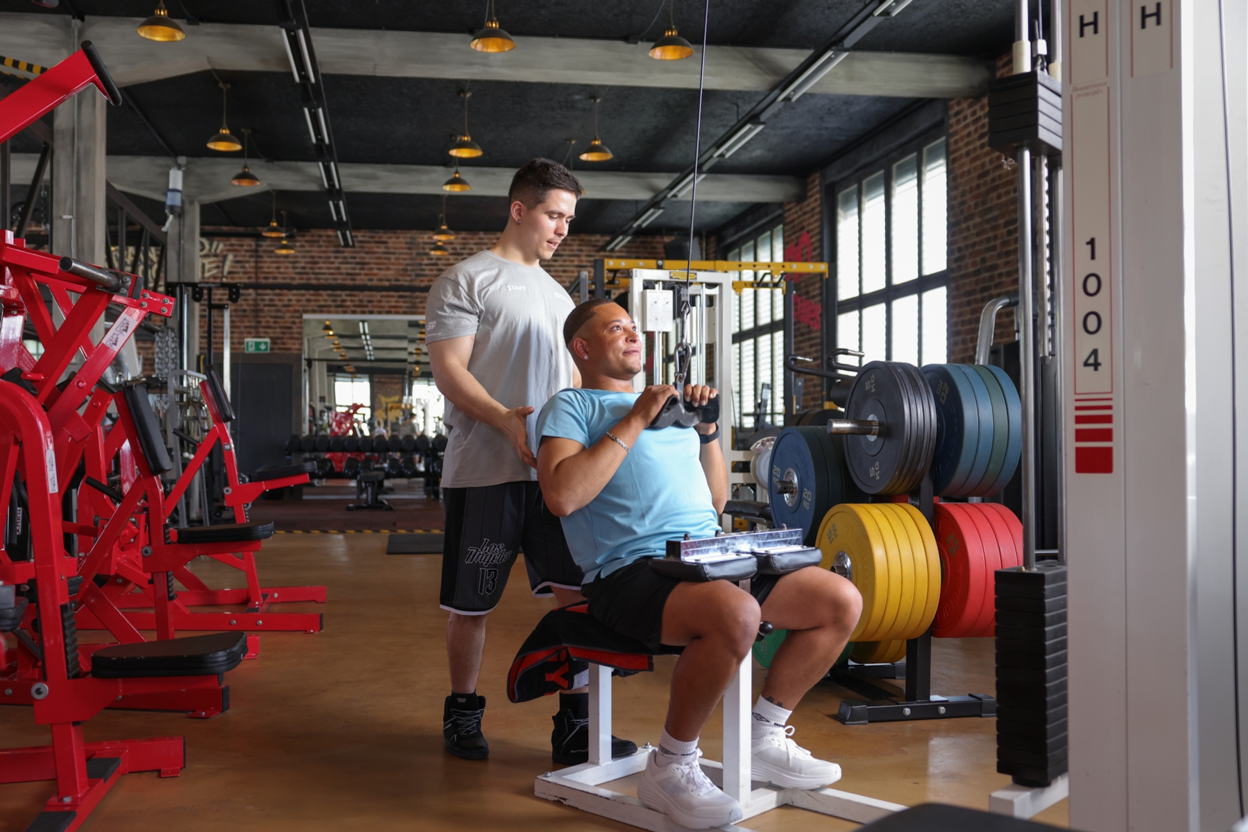 Trainer beim instruieren eines Sportlers auf dem Crosstrainer
