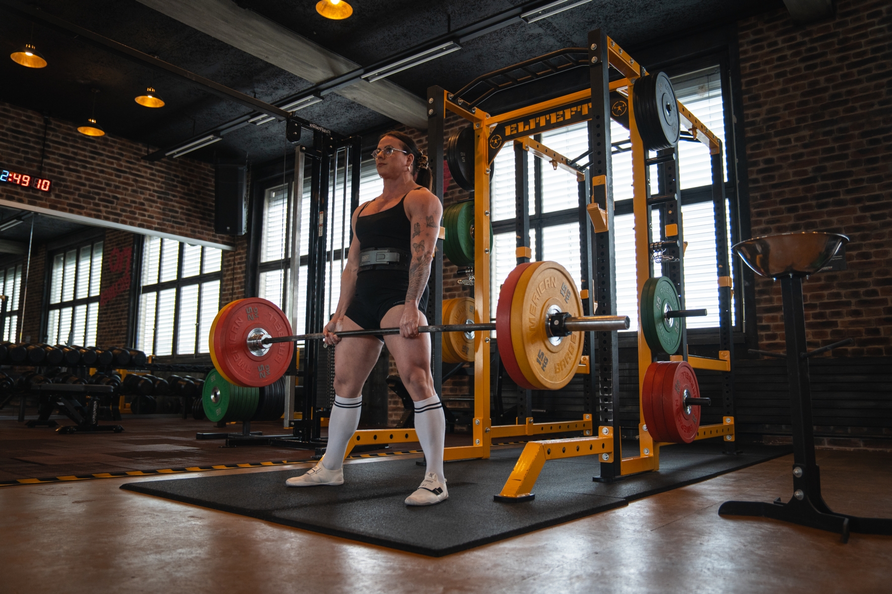 Trainer gibt der Kundin im blauen Top Anweisungen für die Kniebeuge auf dem Bosuball